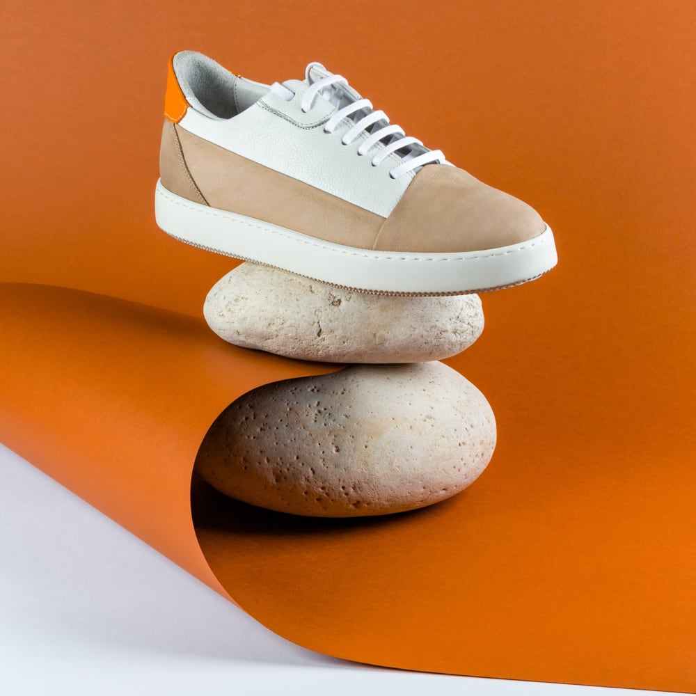a sneaker on two rocks superposed and a orange paper between the rocks